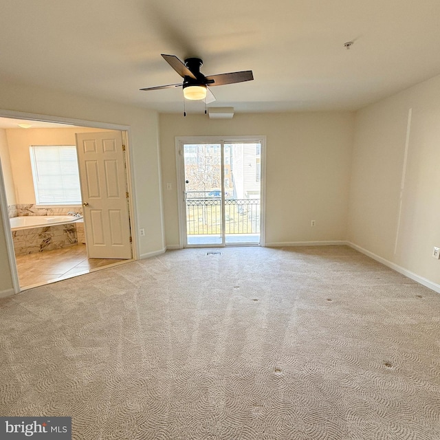 spare room featuring light colored carpet, ceiling fan, and baseboards