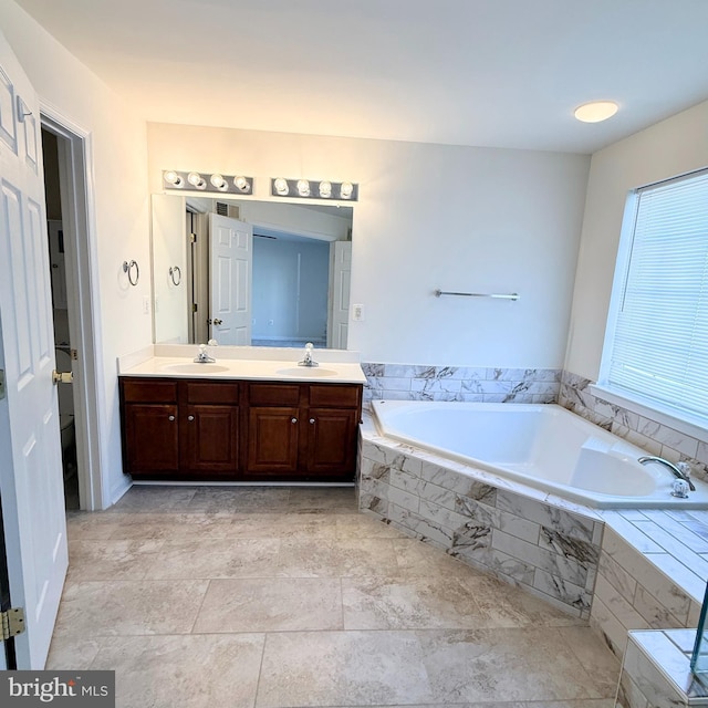 full bath featuring a garden tub, double vanity, and a sink