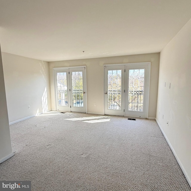 spare room with carpet, visible vents, and baseboards