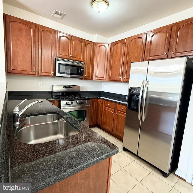 kitchen with visible vents, appliances with stainless steel finishes, brown cabinets, a sink, and light tile patterned flooring