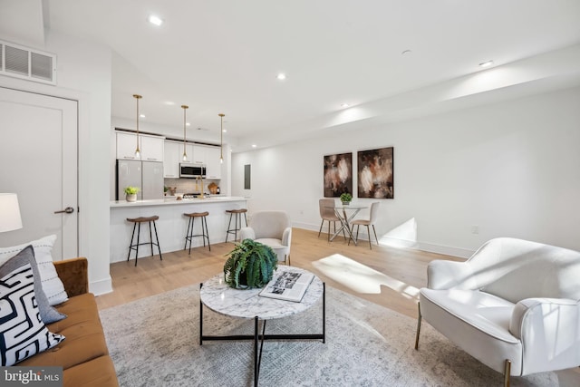 living room featuring baseboards, light wood-style flooring, visible vents, and recessed lighting