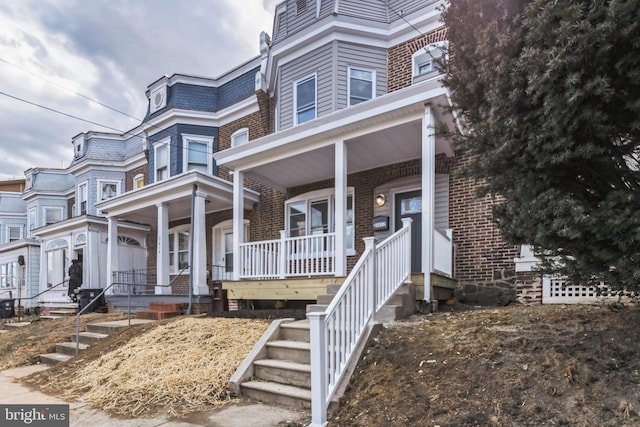 view of front of property with a porch, mansard roof, and brick siding