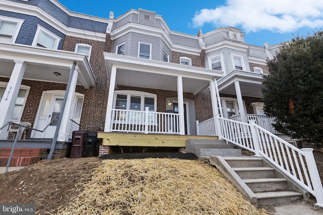 view of property featuring covered porch and brick siding