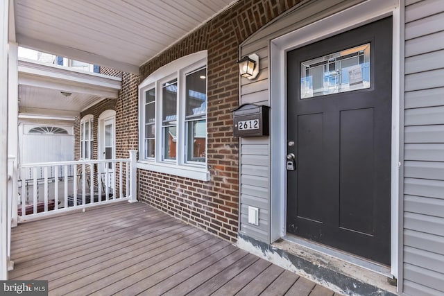 entrance to property featuring covered porch and brick siding