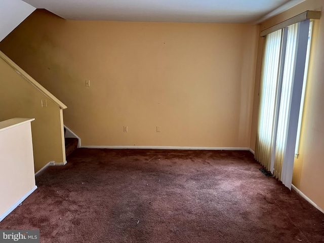 unfurnished living room with lofted ceiling, carpet flooring, baseboards, and stairs