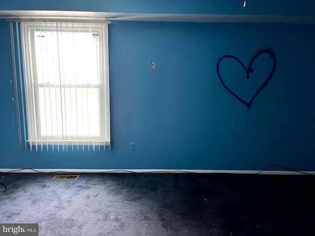 unfurnished room with carpet floors, a healthy amount of sunlight, and visible vents