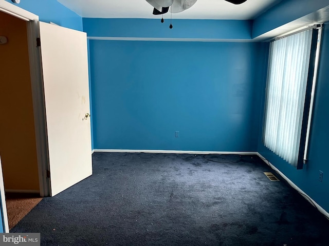 empty room featuring visible vents, a wealth of natural light, and carpet flooring