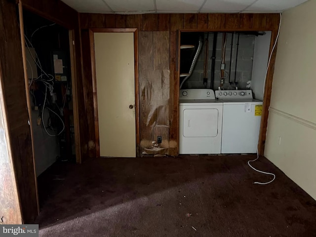 basement with a paneled ceiling, wooden walls, and separate washer and dryer