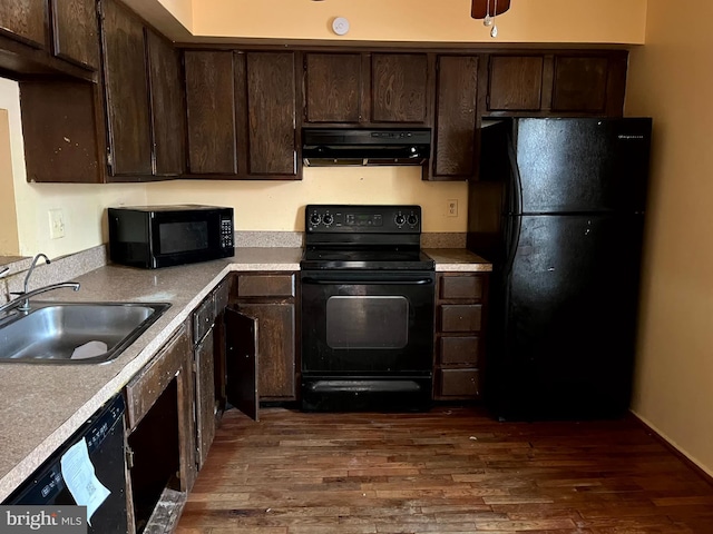 kitchen with dark wood-type flooring, dark brown cabinetry, a sink, black appliances, and exhaust hood