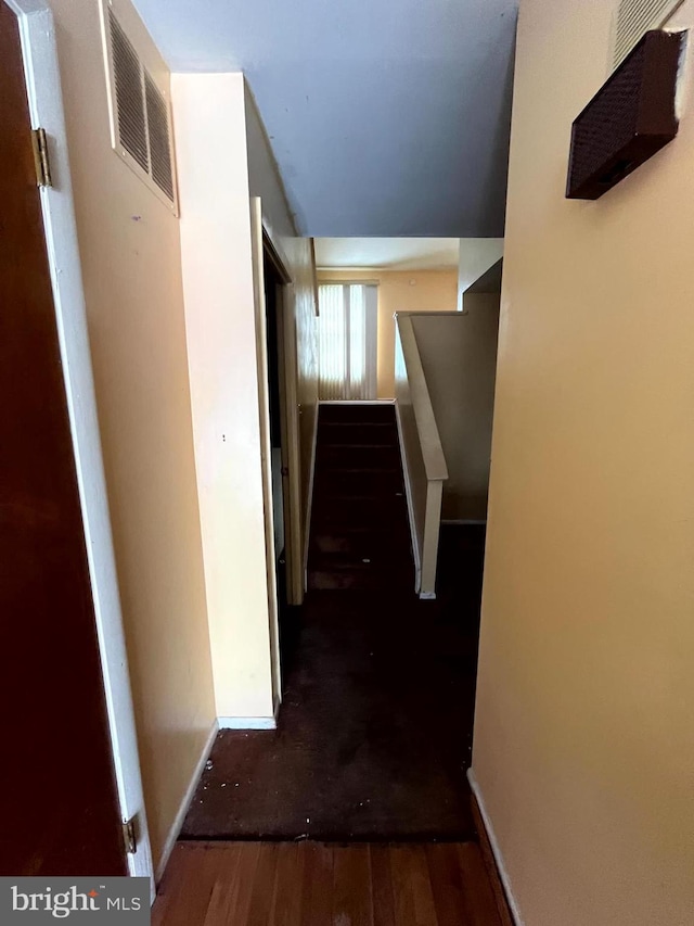 corridor featuring visible vents, stairway, baseboards, and wood finished floors