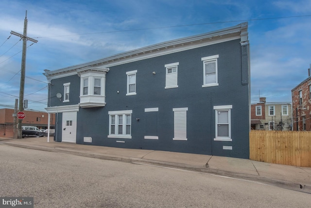 view of front facade with brick siding and fence