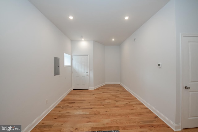 corridor with recessed lighting, electric panel, light wood-style flooring, and baseboards