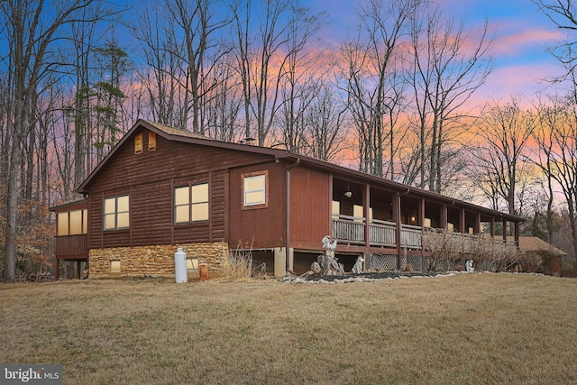 view of side of property featuring stone siding, a porch, and a lawn