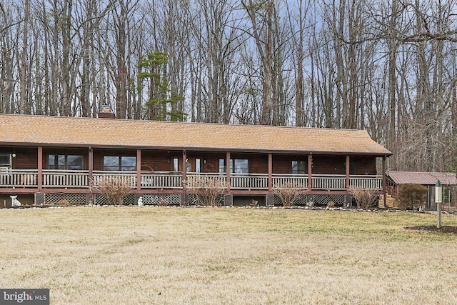 view of front of property featuring roof with shingles, a front lawn, a chimney, and a porch