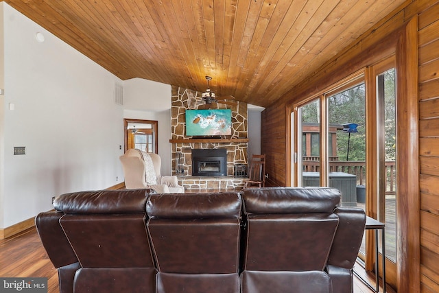 living room with visible vents, wood ceiling, vaulted ceiling, a stone fireplace, and wood finished floors