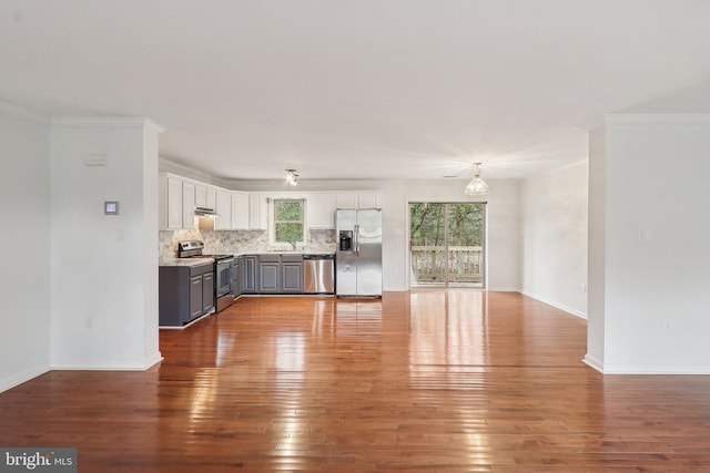 unfurnished living room with a wealth of natural light, baseboards, crown molding, and hardwood / wood-style floors