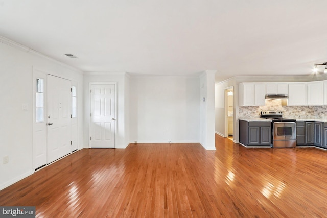 unfurnished living room featuring baseboards, light wood-style flooring, visible vents, and crown molding