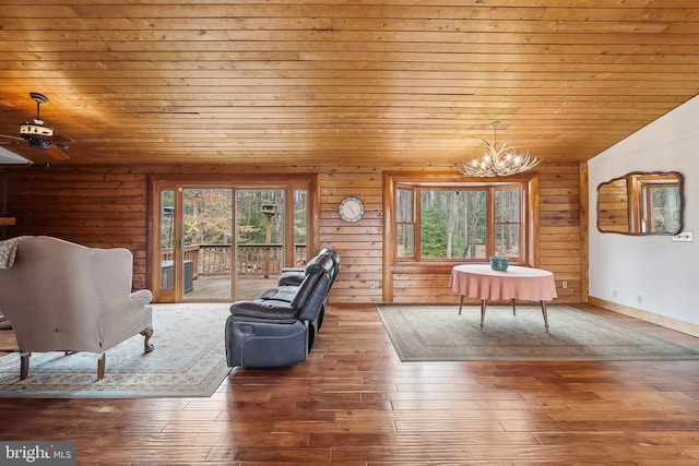 unfurnished living room featuring lofted ceiling, wooden ceiling, wood walls, wood finished floors, and an inviting chandelier