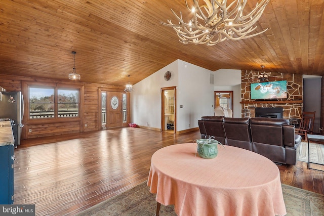 dining room with a chandelier, a fireplace, wood finished floors, wood ceiling, and vaulted ceiling