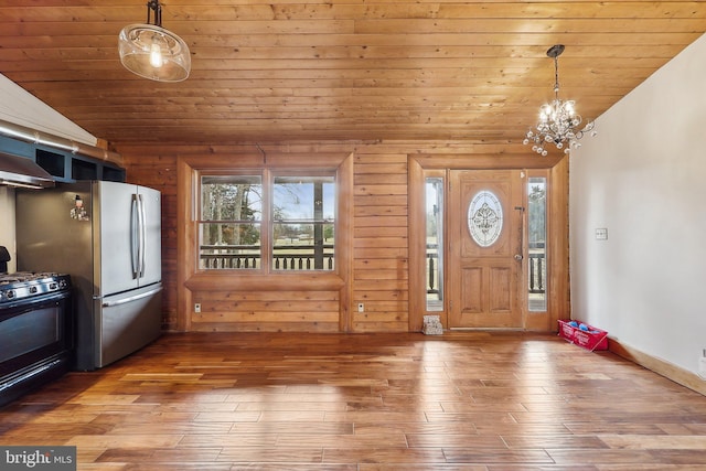 entryway with an inviting chandelier, vaulted ceiling, wood finished floors, wooden ceiling, and baseboards