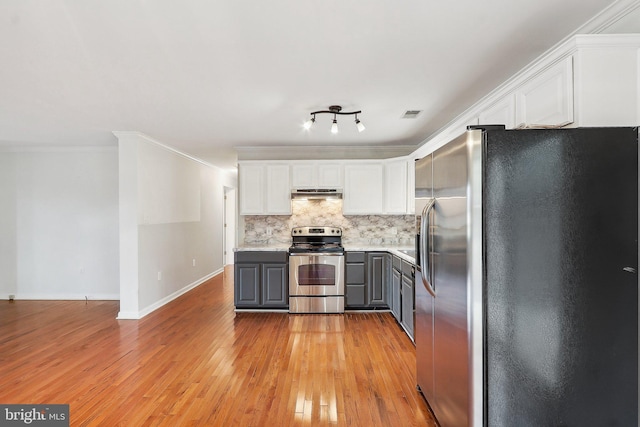 kitchen with white cabinets, appliances with stainless steel finishes, gray cabinetry, under cabinet range hood, and backsplash