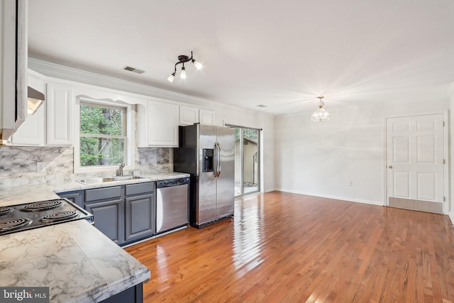 kitchen featuring tasteful backsplash, visible vents, white cabinets, appliances with stainless steel finishes, and a sink