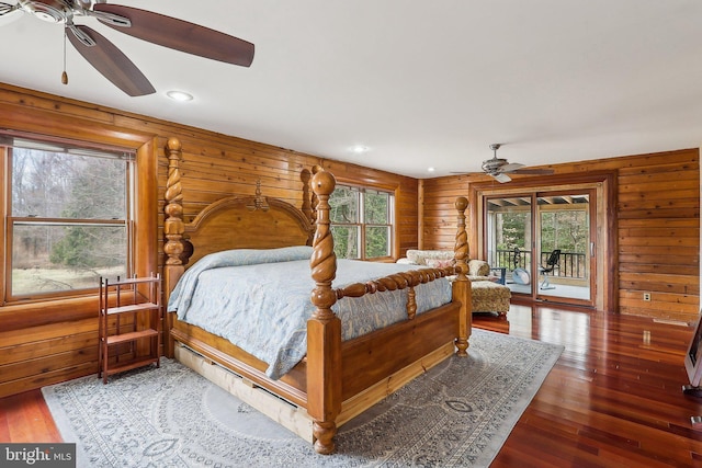 bedroom with access to outside, wood finished floors, and wooden walls