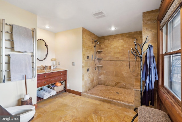 full bathroom featuring baseboards, visible vents, tiled shower, and vanity