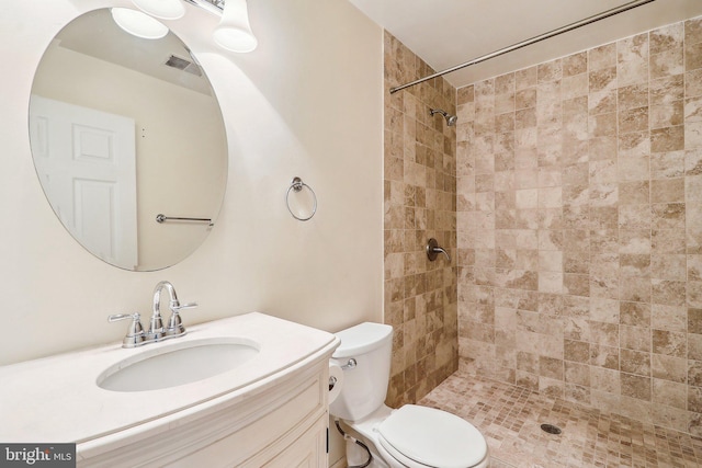 full bathroom with toilet, visible vents, a tile shower, and vanity