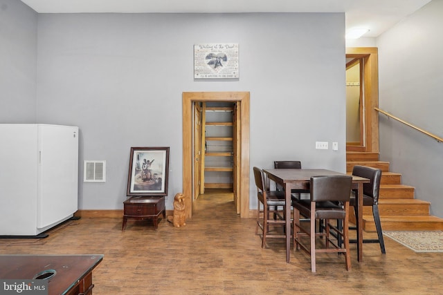 dining space with stairway, wood finished floors, visible vents, and baseboards