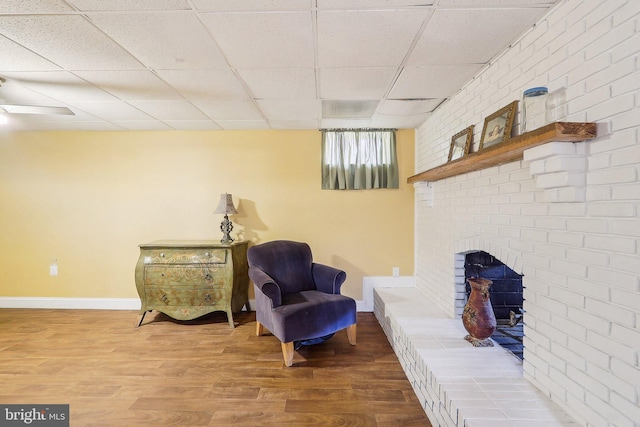 living area with a drop ceiling, wood finished floors, and baseboards