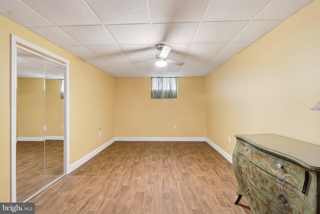 below grade area featuring wood finished floors, a paneled ceiling, and baseboards