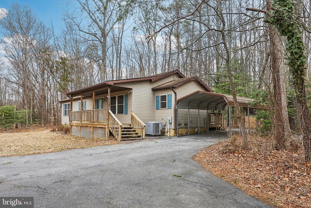 view of front of property with a carport, aphalt driveway, a porch, and central air condition unit