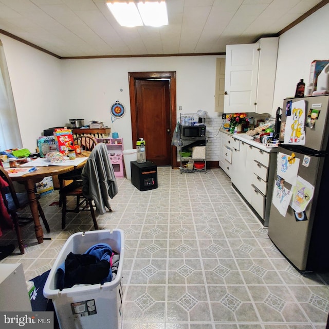 kitchen with white cabinets, ornamental molding, light countertops, and freestanding refrigerator