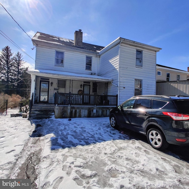 american foursquare style home with covered porch and a chimney