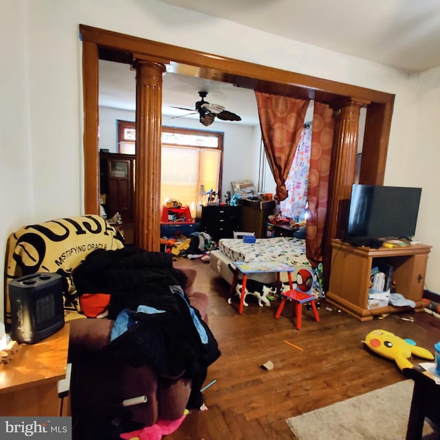 living area with decorative columns, ceiling fan, and wood finished floors