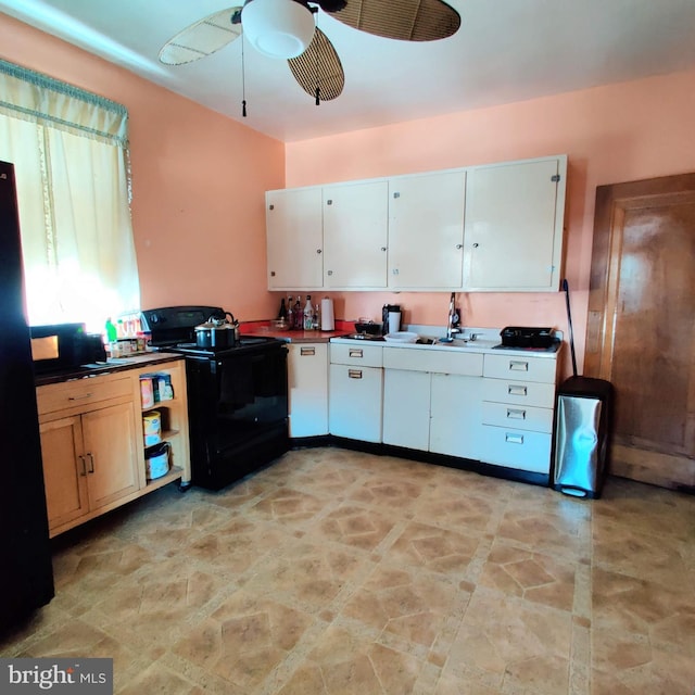 kitchen with a ceiling fan, dark countertops, black appliances, white cabinetry, and a sink