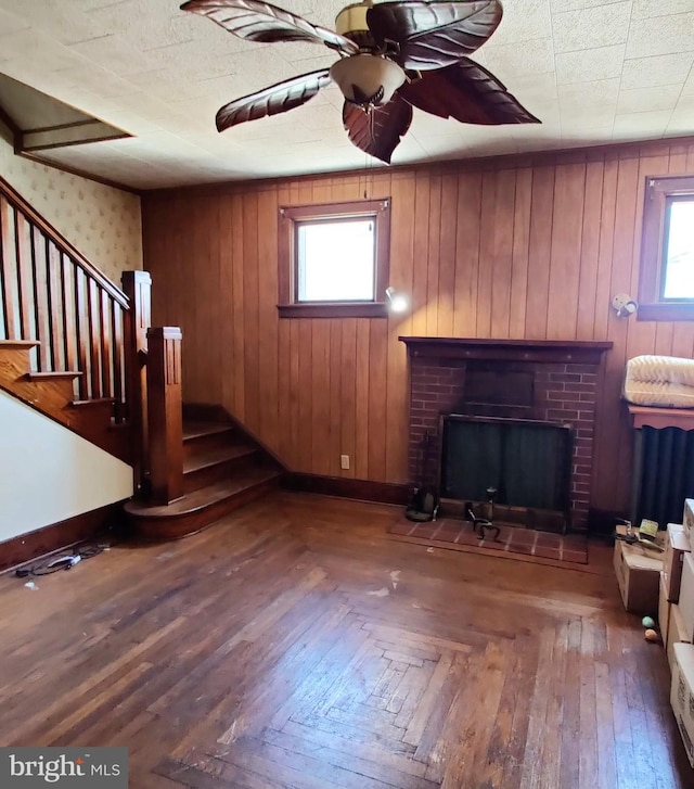 unfurnished living room with ceiling fan, a fireplace, baseboards, parquet floors, and stairway