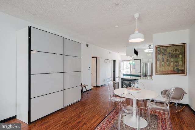 dining room featuring a textured ceiling, baseboards, and wood finished floors