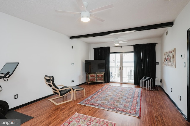 living area featuring beamed ceiling, wood finished floors, and baseboards