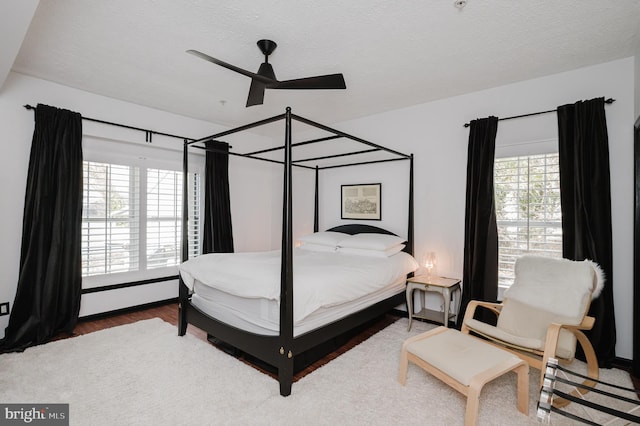 bedroom featuring a baseboard heating unit, ceiling fan, a textured ceiling, and wood finished floors