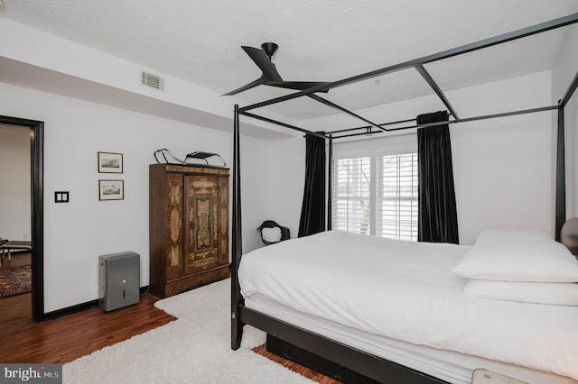 bedroom featuring a textured ceiling, wood finished floors, visible vents, and baseboards