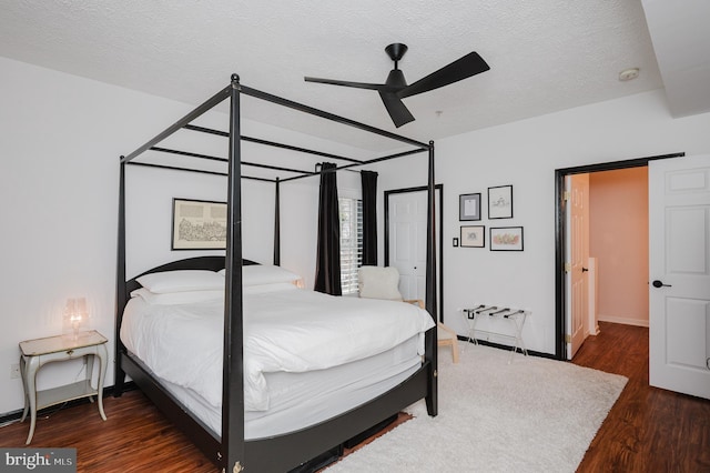 bedroom with ceiling fan, a textured ceiling, baseboards, and wood finished floors