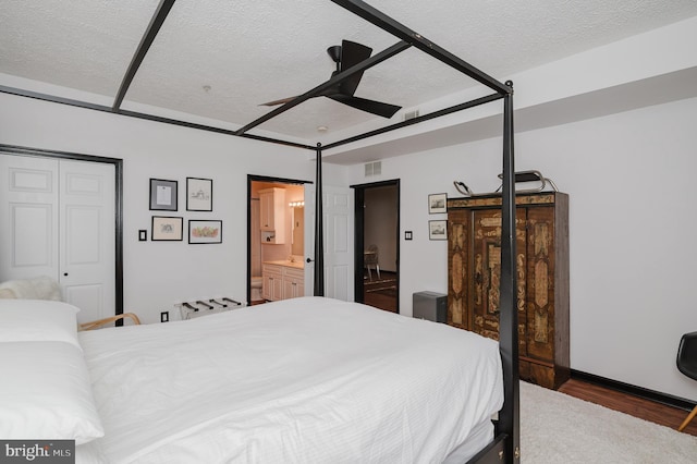 bedroom with visible vents, connected bathroom, a textured ceiling, and wood finished floors