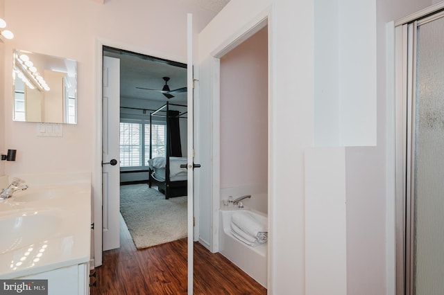 full bathroom featuring a garden tub, double vanity, wood finished floors, and a sink