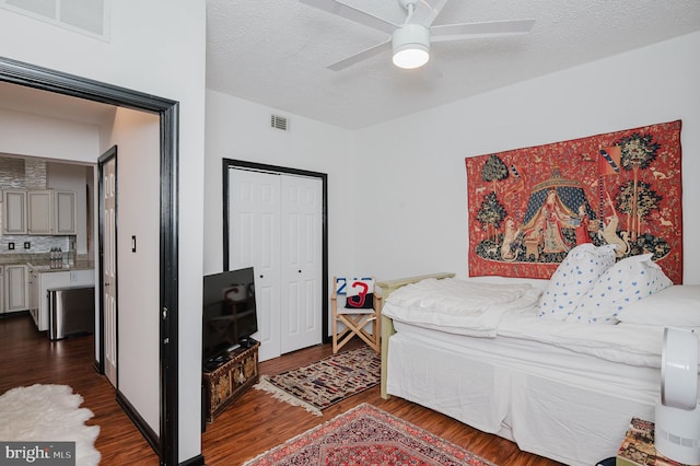 bedroom featuring dark wood-style floors, a closet, visible vents, and a textured ceiling