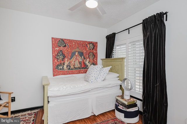 bedroom featuring a ceiling fan, baseboards, a textured ceiling, and wood finished floors