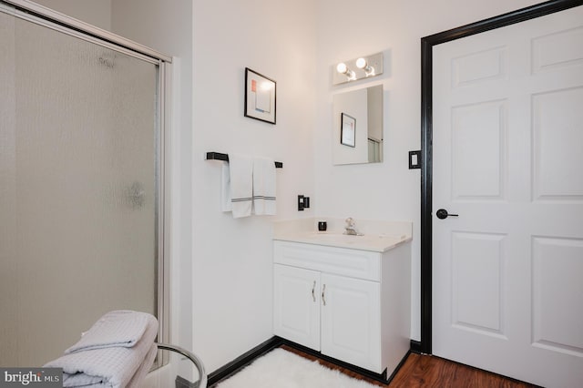 full bath with a stall shower, vanity, and wood finished floors