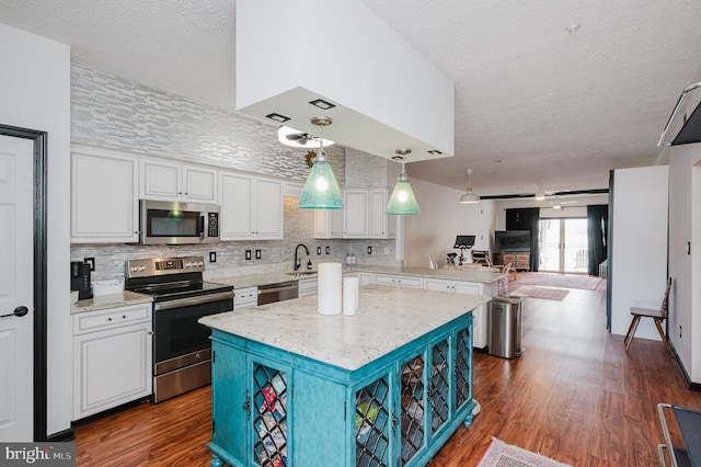 kitchen with open floor plan, stainless steel appliances, dark wood-style floors, and white cabinetry