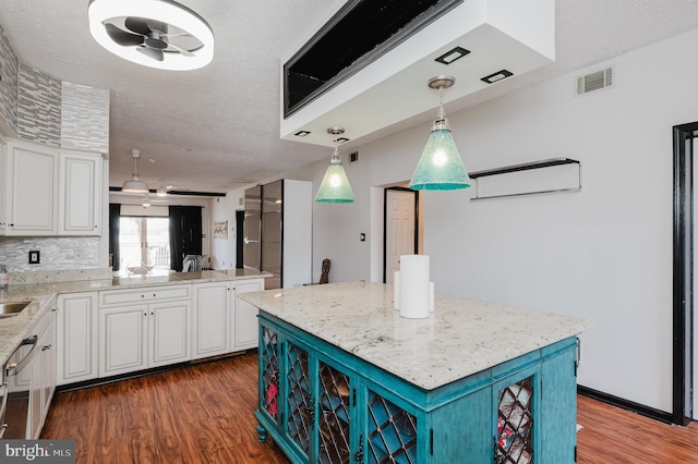 kitchen with light stone countertops, visible vents, white cabinets, and wood finished floors